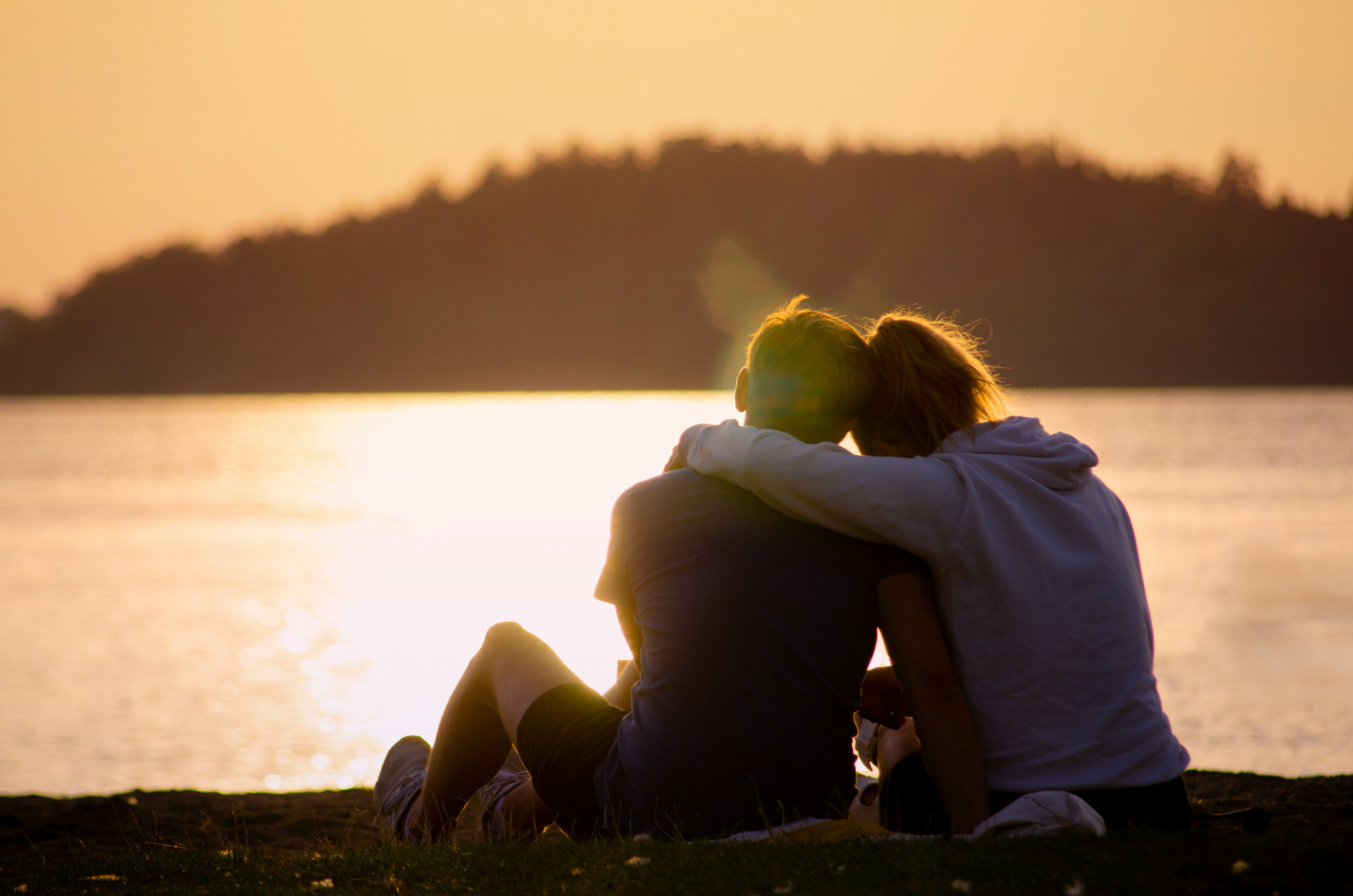 Two people sitting together at a lake