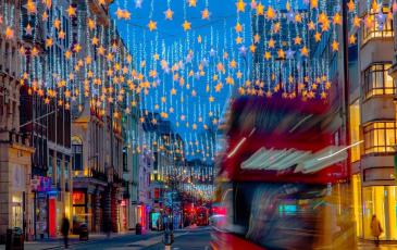 Image shows a town centre with Christmas lights and a bus