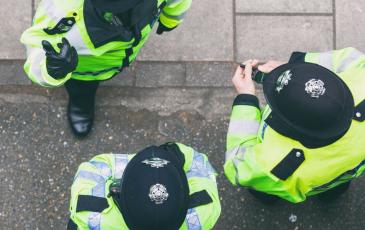 Image shows 3 uniformed police officers talking. 