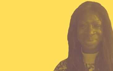 Fatou is smiling at the camera, she has black hair and skin and she is wearing a geometric pattern jumper