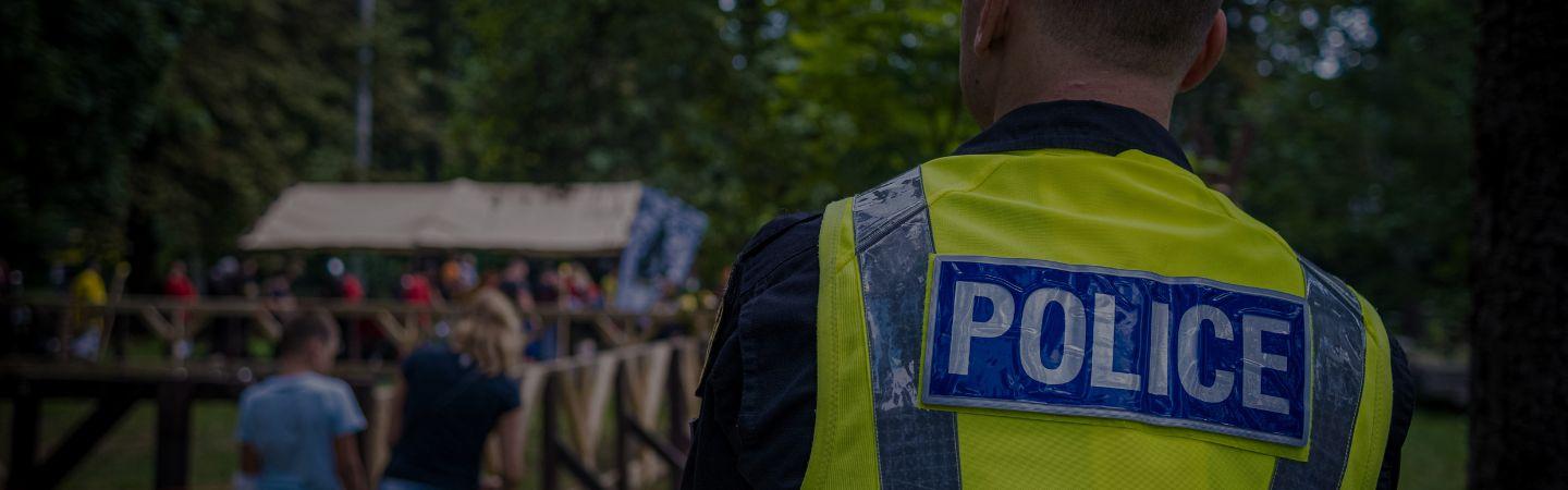 Image shows a police officer in a high vis vest providing security for a community event
