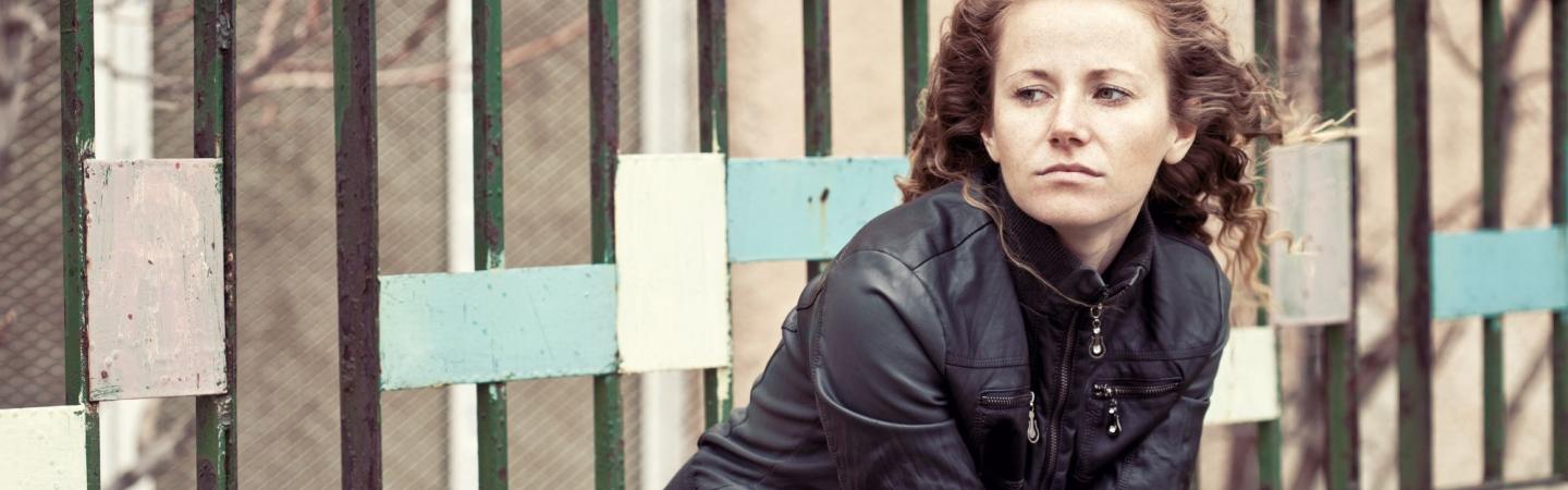 Image shows a young woman in a leather jacket she looks pensive